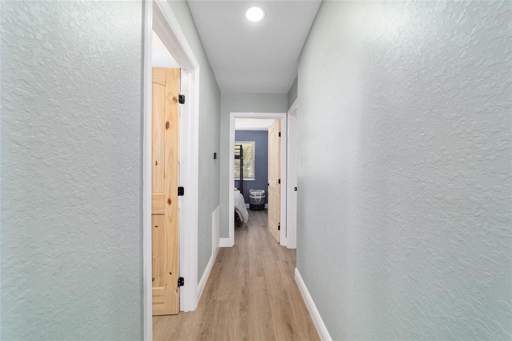 24628 Fox Road Astor, FL 32102 - Photo 93 of 96 a view of a hallway with wooden floor and a bathroom