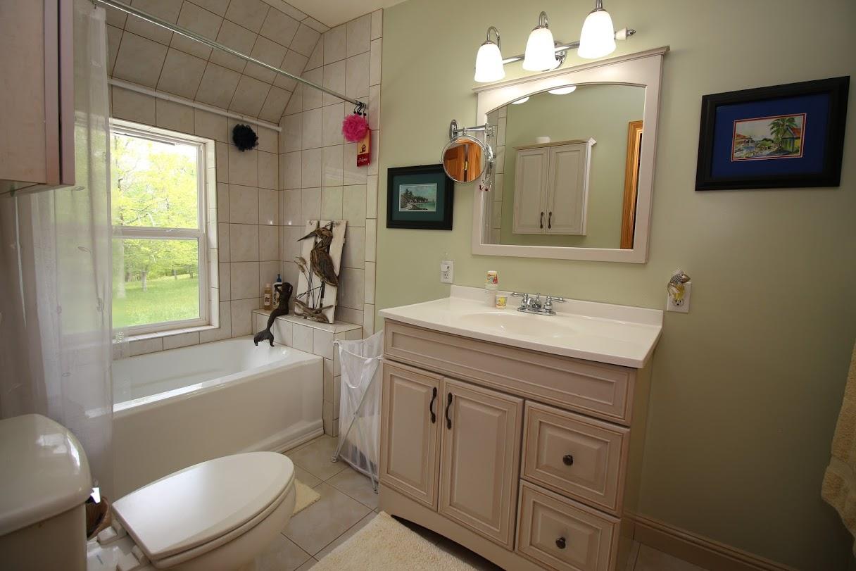 2185 Loops Road Rainelle, WV 25962 - Photo 89 of 109 a bathroom with a granite countertop toilet a sink a mirror and a window