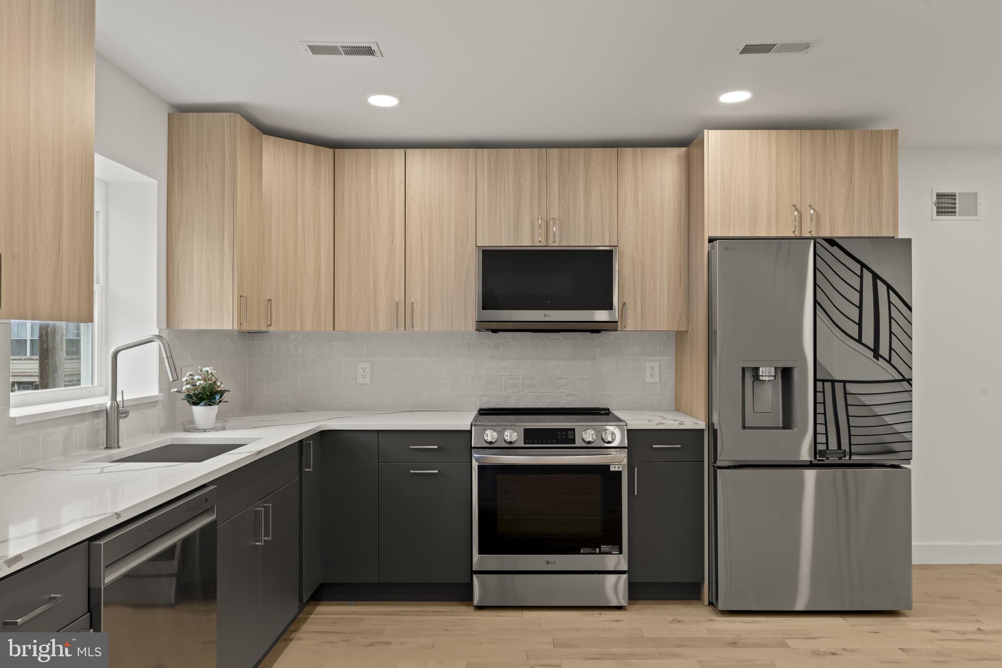 2747 South Beulah Street Philadelphia, PA 19148 - Photo 8 of 37 a kitchen with stainless steel appliances a refrigerator a sink a stove a microwave and wooden cabinets