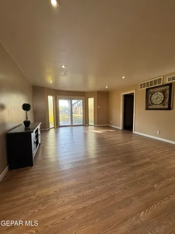 a view of a livingroom with wooden floor and an empty room