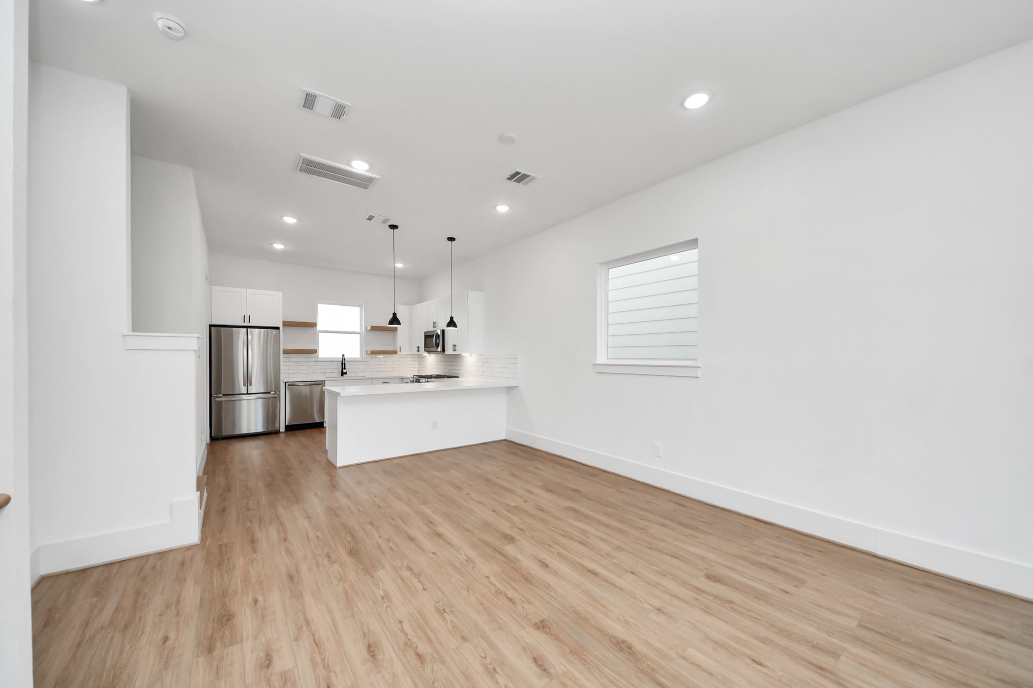 4806 Cochran Street Houston, TX 77009 - Photo 13 of 43 a view of a kitchen with kitchen island a sink wooden floor and a refrigerator