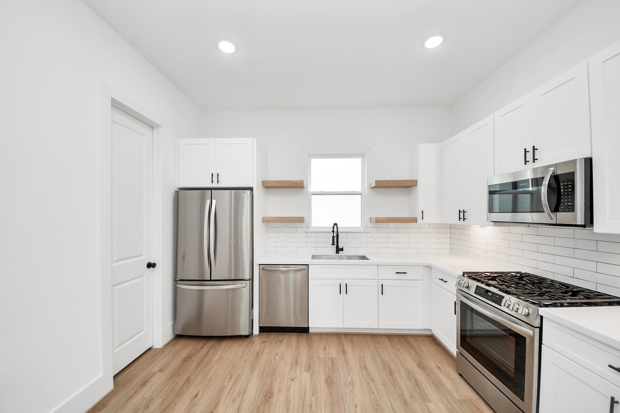 4806 Cochran Street Houston, TX 77009 - Photo 15 of 43 a kitchen with stainless steel appliances a sink dishwasher a refrigerator and a stove with wooden floor