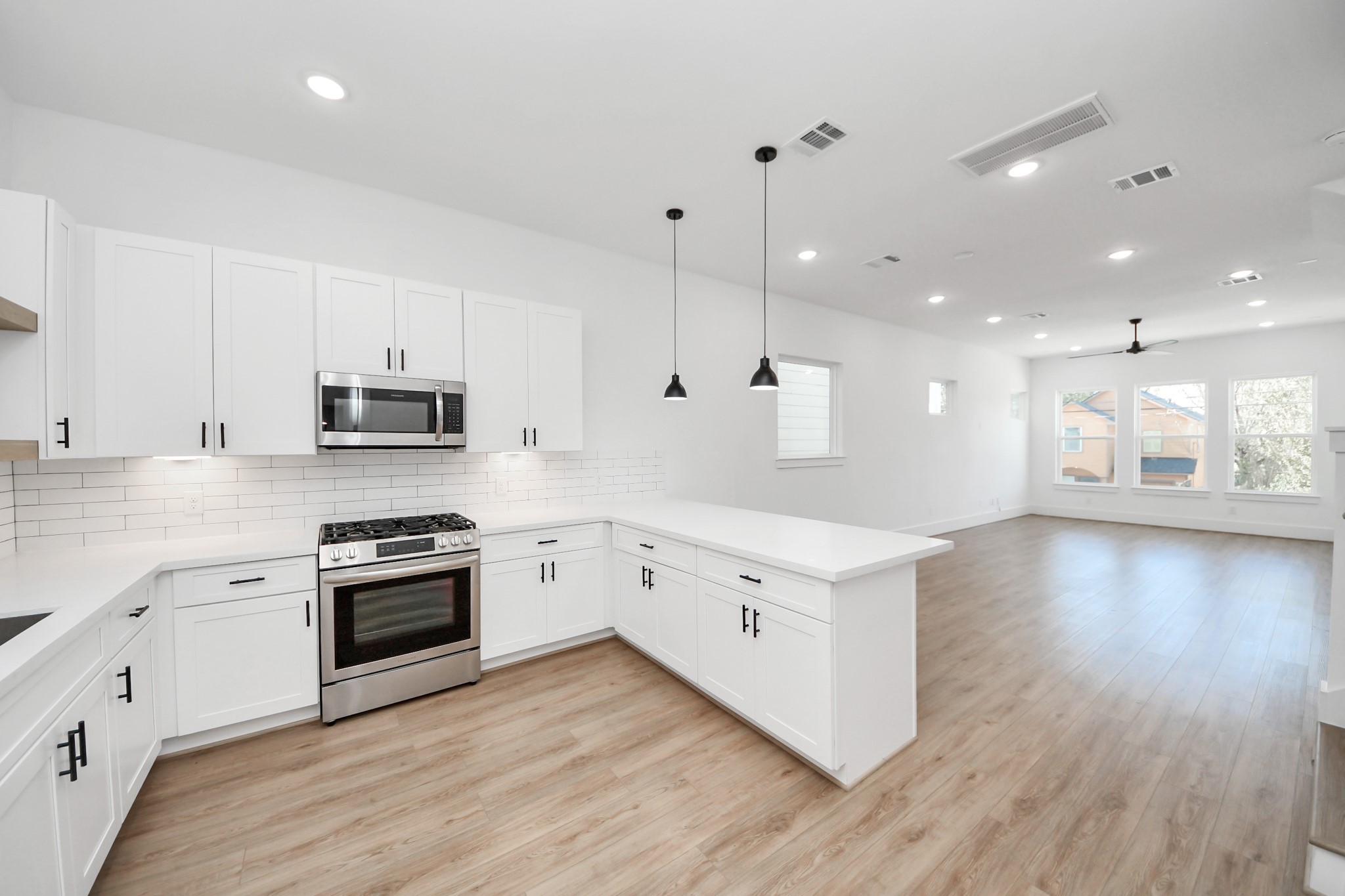 4806 Cochran Street Houston, TX 77009 - Photo 17 of 43 a large white kitchen with stainless steel appliances granite countertop a stove oven a sink dishwasher and white cabinets with wooden floor
