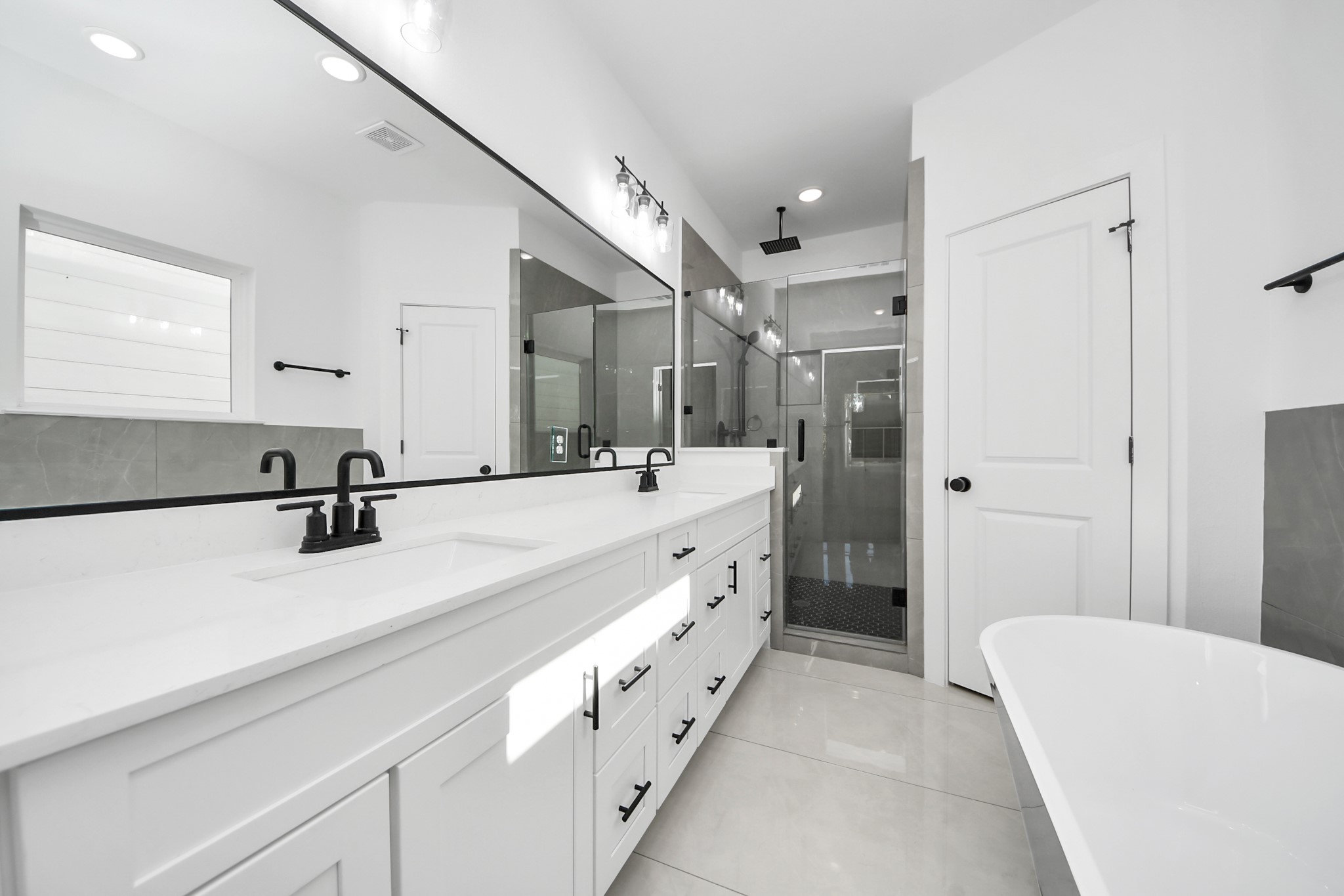 4806 Cochran Street Houston, TX 77009 - Photo 28 of 43 a large white bathroom with a double vanity sink a mirror and a bathtub