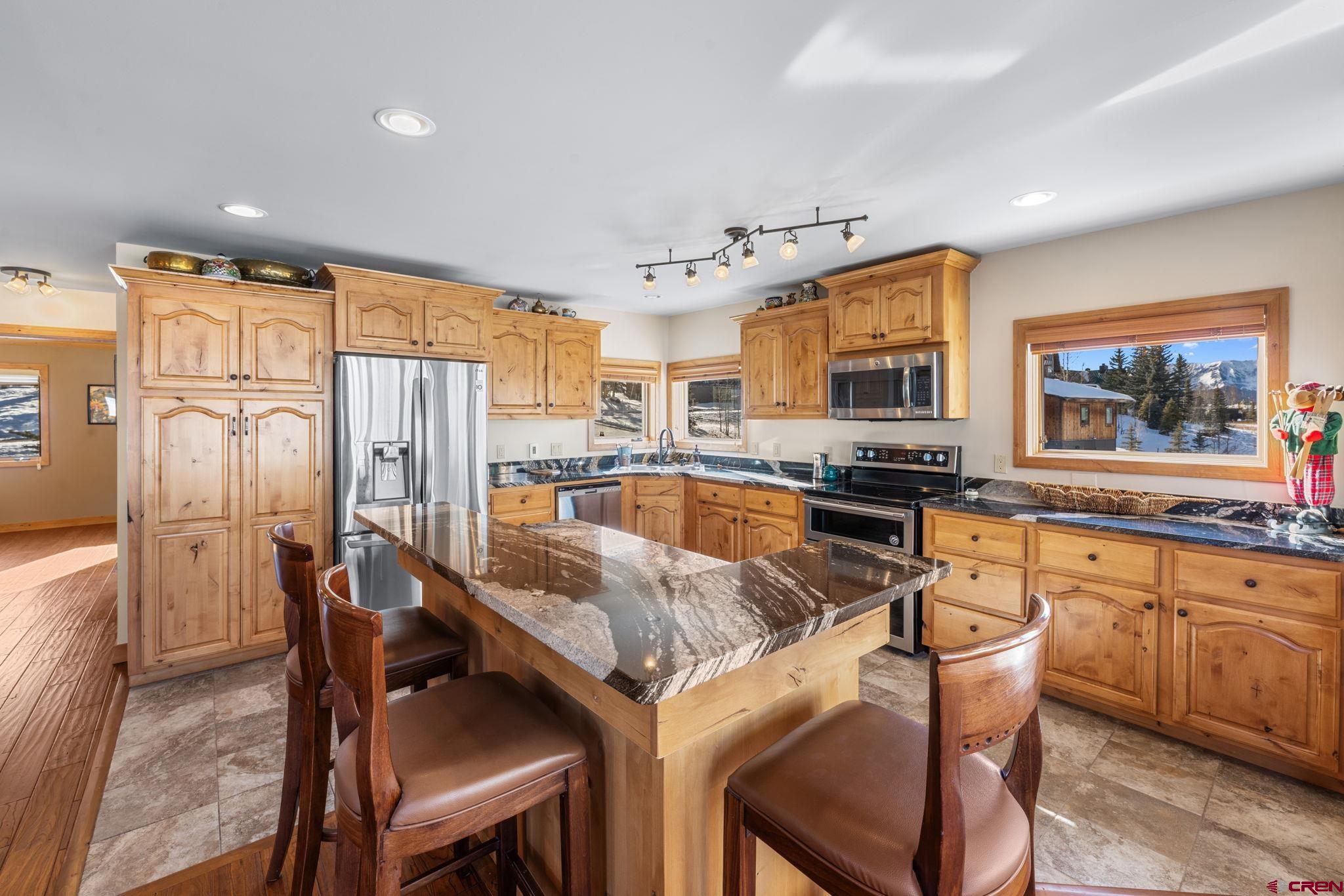 10 Ruby Drive Crested Butte, CO 81225 - Photo 11 of 42 a kitchen with stainless steel appliances granite countertop a table chairs sink refrigerator and microwave