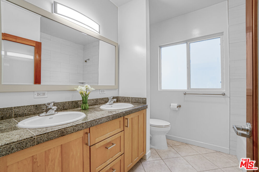 120 Fleet Street, Unit B Marina del Rey, CA 90292 - Photo 26 of 32 a bathroom with a granite countertop sink a toilet and a mirror