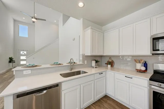 a kitchen with a sink dishwasher and white cabinets with wooden floor