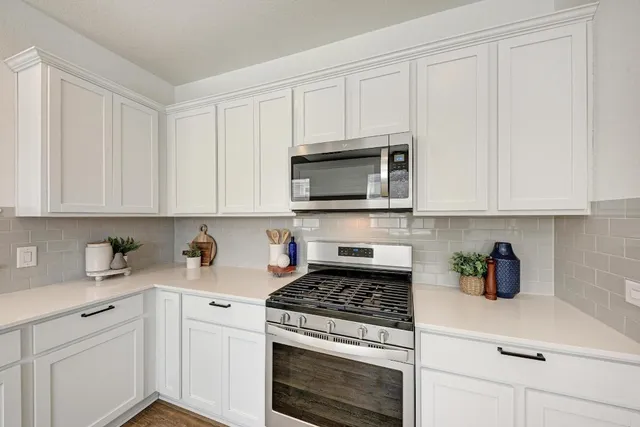 a kitchen with white cabinets and appliances