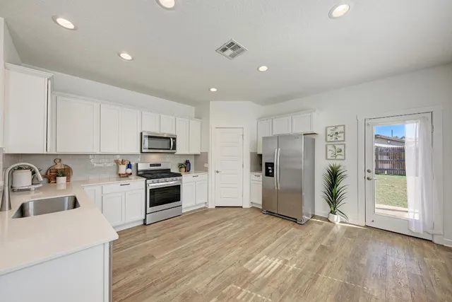 a kitchen with stainless steel appliances a refrigerator sink and microwave