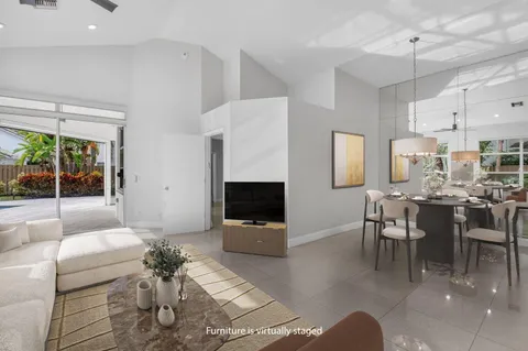 a living room with furniture potted plant a flat screen tv and kitchen view