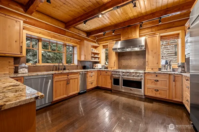 a large kitchen with granite countertop a stove top oven a sink and dishwasher