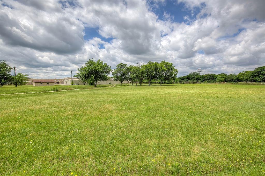 221 Maple Street Commerce, TX 75428 - Photo 14 of 19 a view of a big yard with lawn chairs and a fountain