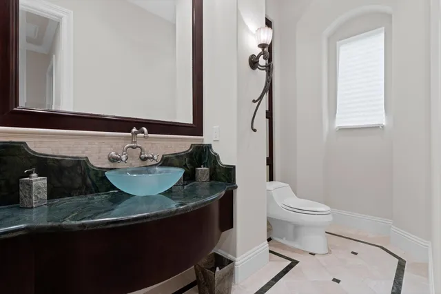 a bathroom with a granite countertop sink toilet and mirror