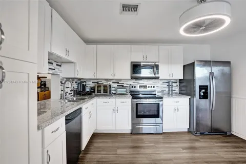 a kitchen with stainless steel appliances granite countertop a sink a stove a refrigerator and a microwave