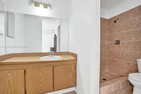 a bathroom with a granite countertop sink a toilet and shower