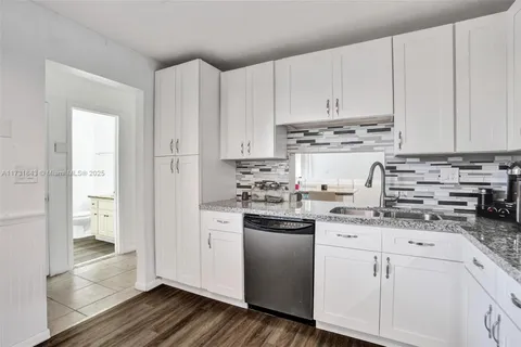 a kitchen with stainless steel appliances granite countertop a refrigerator sink and white cabinets
