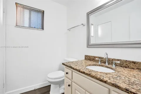 a bathroom with a granite countertop sink and a toilet