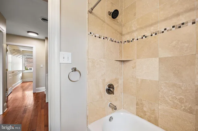 a bathroom with a tub shower sink and mirror