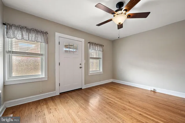 a view of an empty room with wooden floor and a window