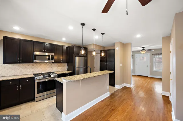 a kitchen with stainless steel appliances granite countertop a sink a stove and a wooden floors