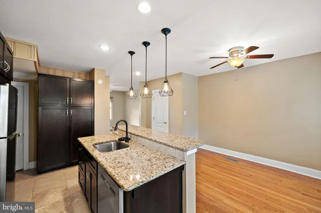 a kitchen with stainless steel appliances granite countertop a sink a refrigerator and chandelier