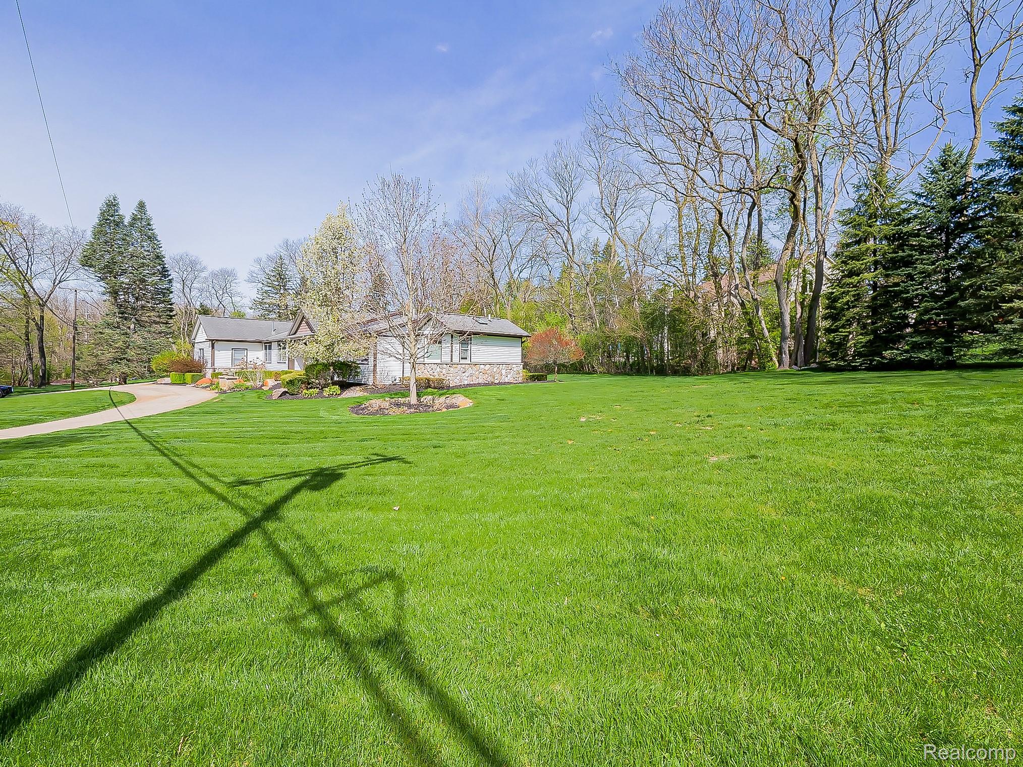 3720 East Clarkston Road Oakland, MI 48363 - Photo 47 of 60 View of grassy yard featuring view of wooded area, an attached garage, and driveway