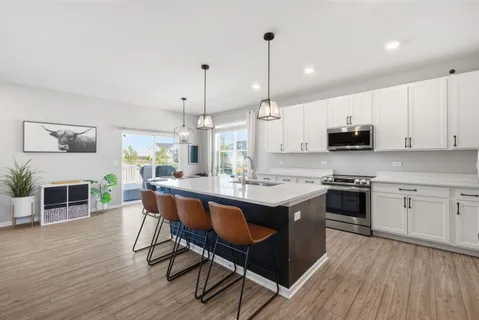 a kitchen with stainless steel appliances granite countertop a stove a sink dishwasher a microwave oven and a dining table with wooden floor