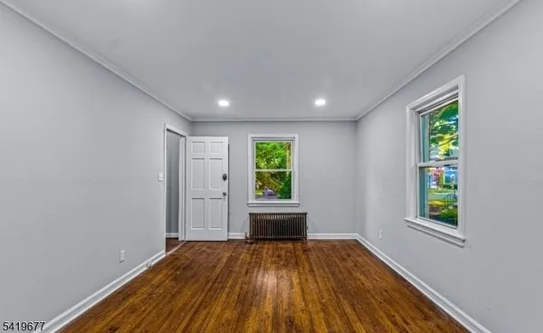 a view of empty room with window and wooden floor