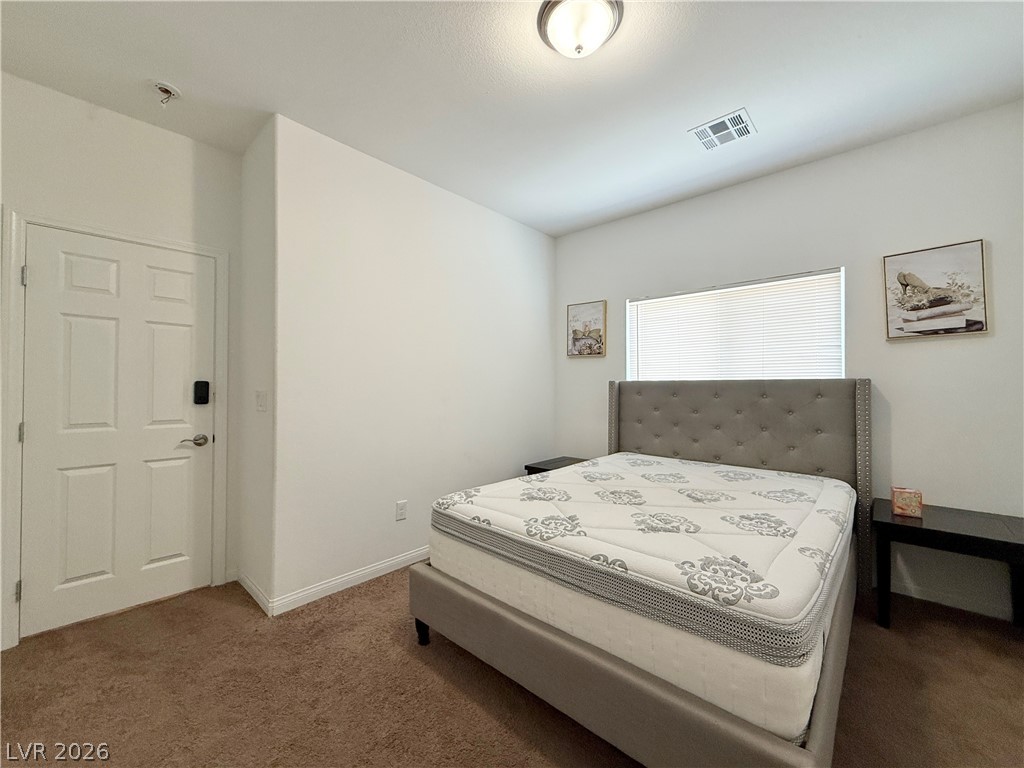7777 South Westwind Road Las Vegas, NV 89139 - Photo 21 of 46 A well-lit bedroom features plush carpeting and a wide window with blinds.