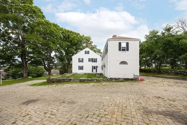 a view of a white house with a yard and large trees
