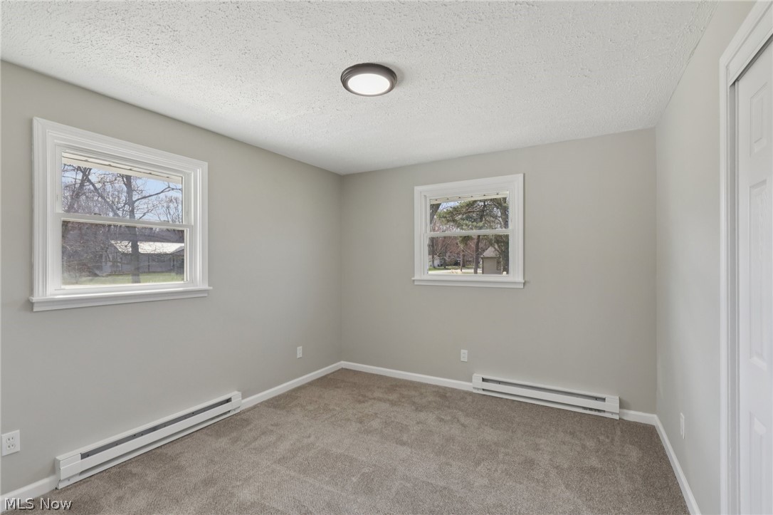 7412 Hopkins Road Mentor, OH 44060 - Photo 22 of 36 Spare room with baseboard heating, light carpet, and a textured ceiling