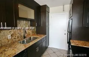a kitchen with granite countertop a sink and a refrigerator