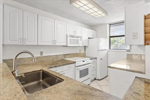 a kitchen with granite countertop a sink stainless steel appliances and white cabinets