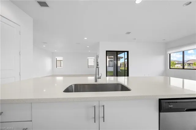 a kitchen with granite countertop a sink and white cabinets