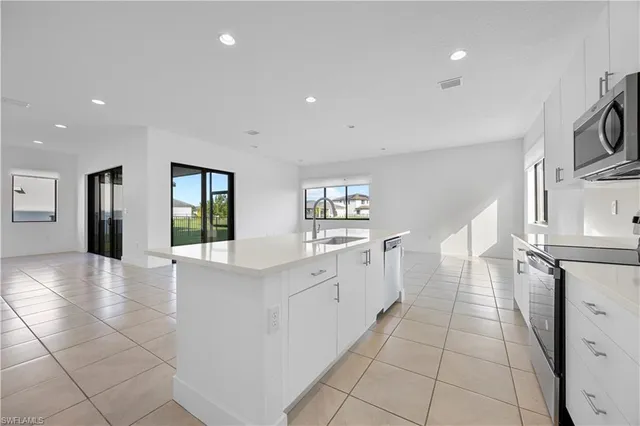 a large white kitchen with a sink and dishwasher with a fireplace