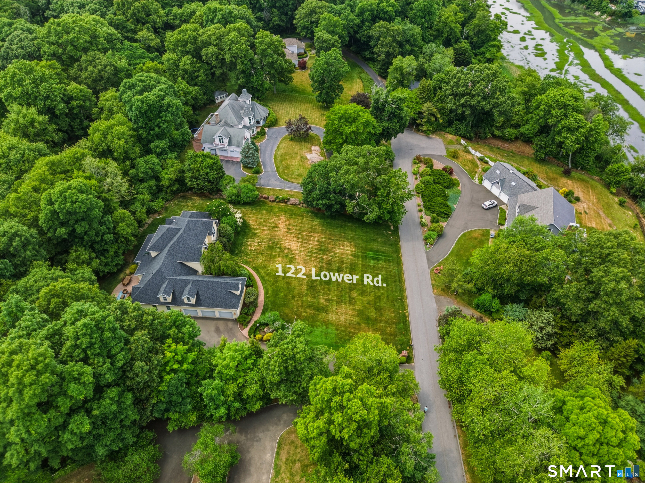 122 Lower Road Guilford, CT 06437 - Photo 33 of 39 Aerial view of the property showcasing the home, yard, surrounding neighborhood, and nearby salt marsh, highlighting the beautiful coastal setting and natural surroundings.