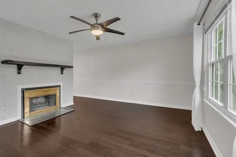 an empty room with wooden floor a ceiling fan and a fireplace