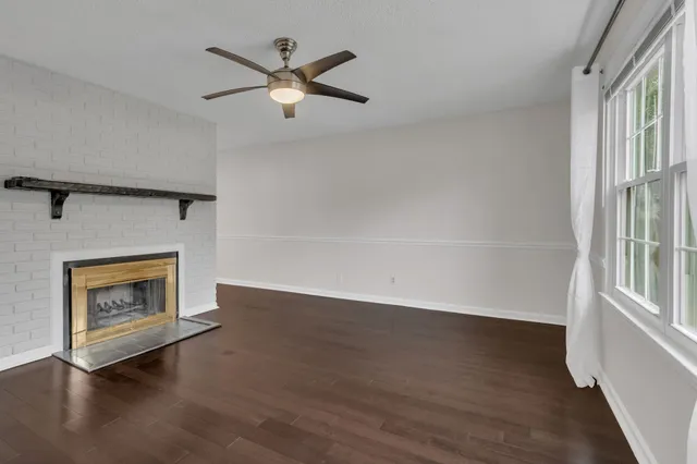 an empty room with wooden floor a ceiling fan and a fireplace