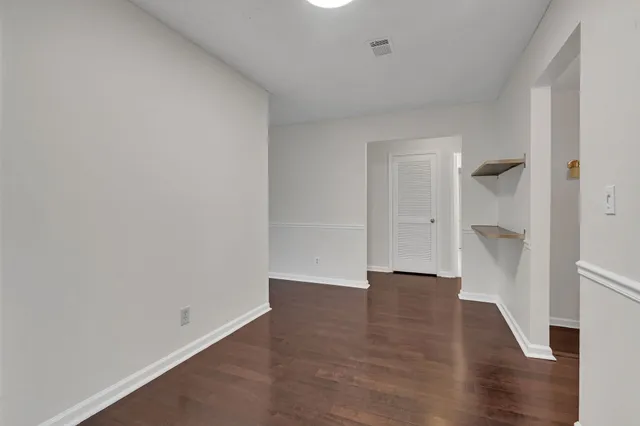 a view of an empty room with wooden floor and a sink