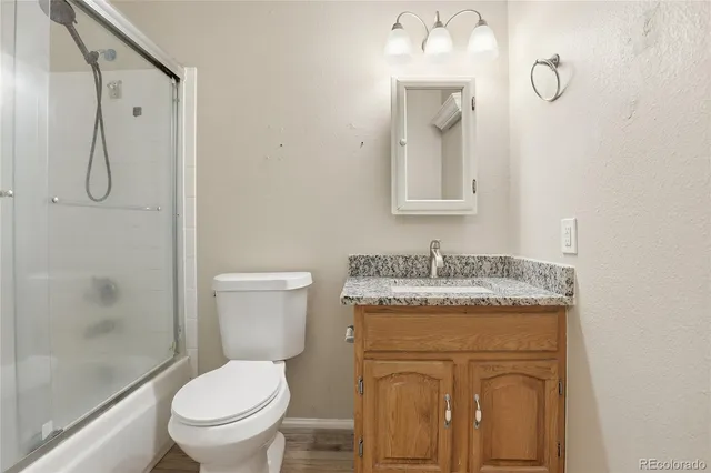 a bathroom with a granite countertop toilet a sink and mirror
