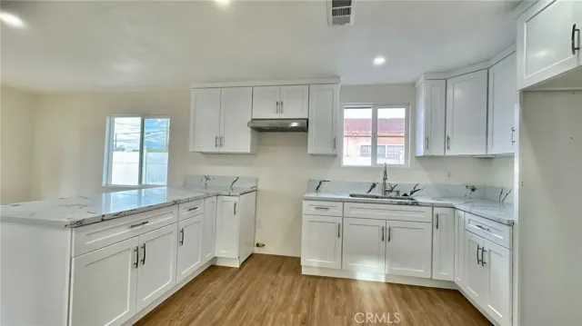 a kitchen with stainless steel appliances a sink cabinets and wooden floor