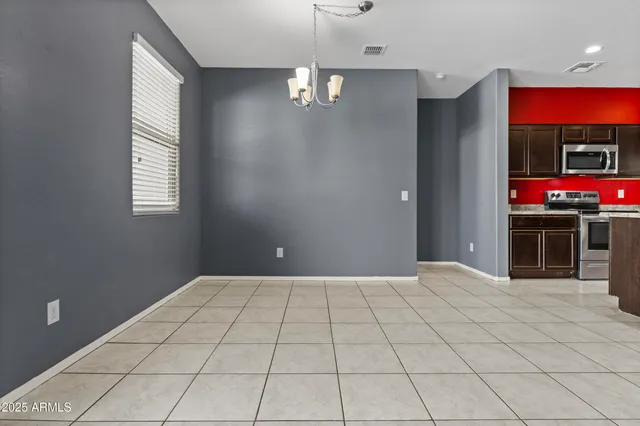 a view of an empty room with window and chandelier