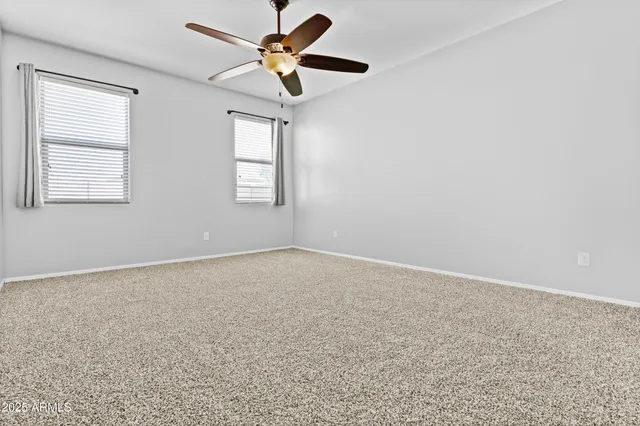 an empty room with ceiling fan and window