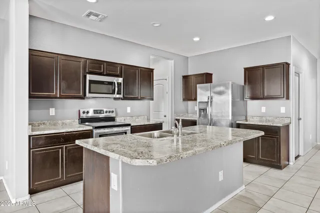 a kitchen with stainless steel appliances granite countertop a sink stove microwave and refrigerator