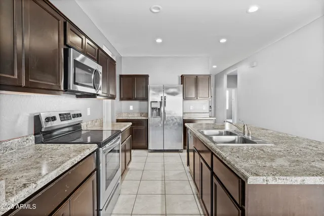 a kitchen with stainless steel appliances granite countertop a sink stove and refrigerator