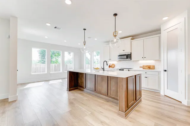 a kitchen with kitchen island granite countertop a sink appliances and cabinets