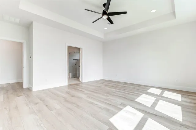 a view of empty room with wooden floor and fan