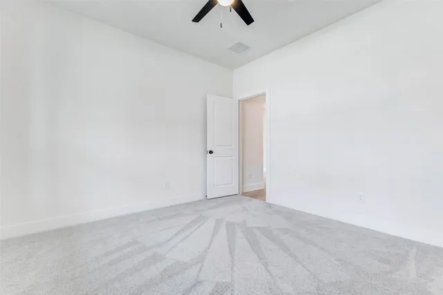 an empty room with ceiling fan and window