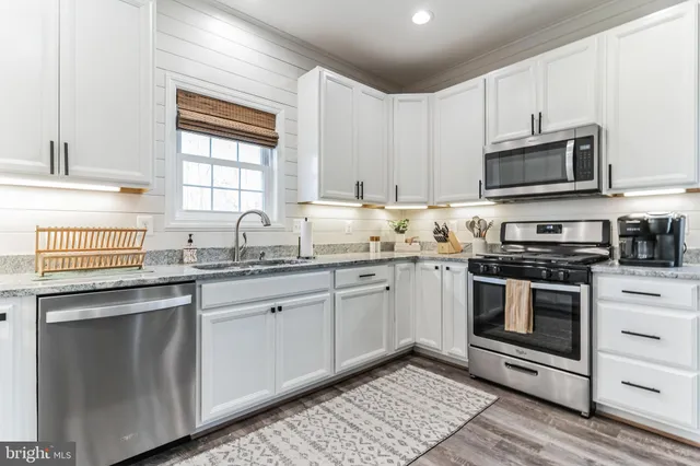 a kitchen with granite countertop a sink stainless steel appliances and cabinets