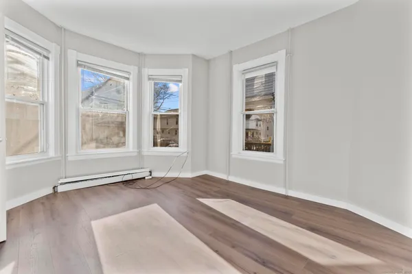 a view of an empty room with a window and wooden floor